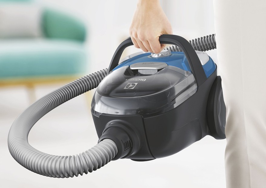 Podlahový vysavač Electrolux CompactGo Cyclonic ECGC21-2CB modrý Žena drží za madlo vysavač Electrolux ECGC21-2CB CompactGo Cyclonic