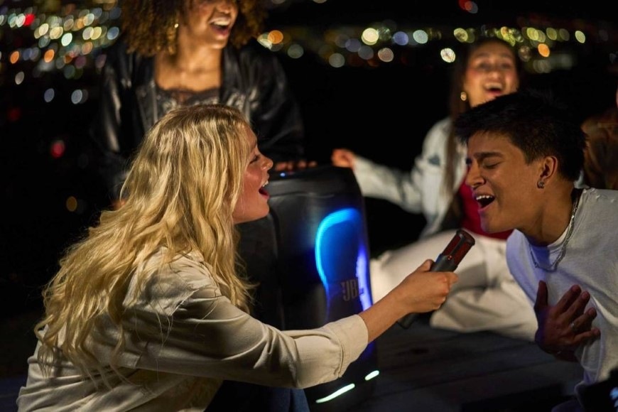 Skupina lidí se baví při karaoke díky reproduktoru JBL PartyBox 130 se vstupem pro mikrofon
