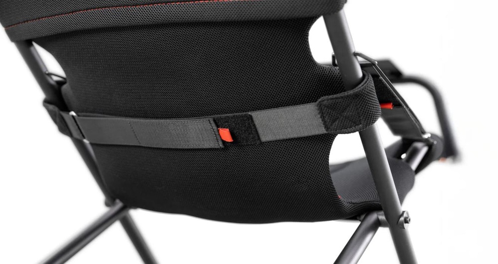  Detailní záběr na černé síťované opěradlo židle s nastavitelným bederním opěrným pásem a oranžovými detaily. Design je moderní, s důrazem na pohodlí a ergonomii.