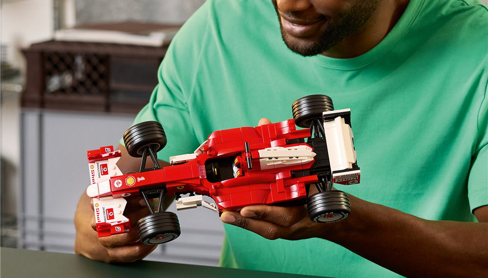 Minifigurka Michaela Schumachera s helmou a trofejí doplňuje podstavce s informacemi o legendárním Ferrari F2004.