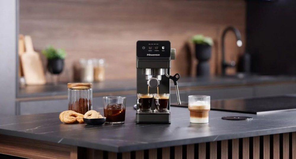 Espresso Hisense HESCM20LP antracitový pákový kávovar Hisense HESCM20LP na tmave kuchynské lince připravuje dvě espressa, vedle stojí nachystane latte.