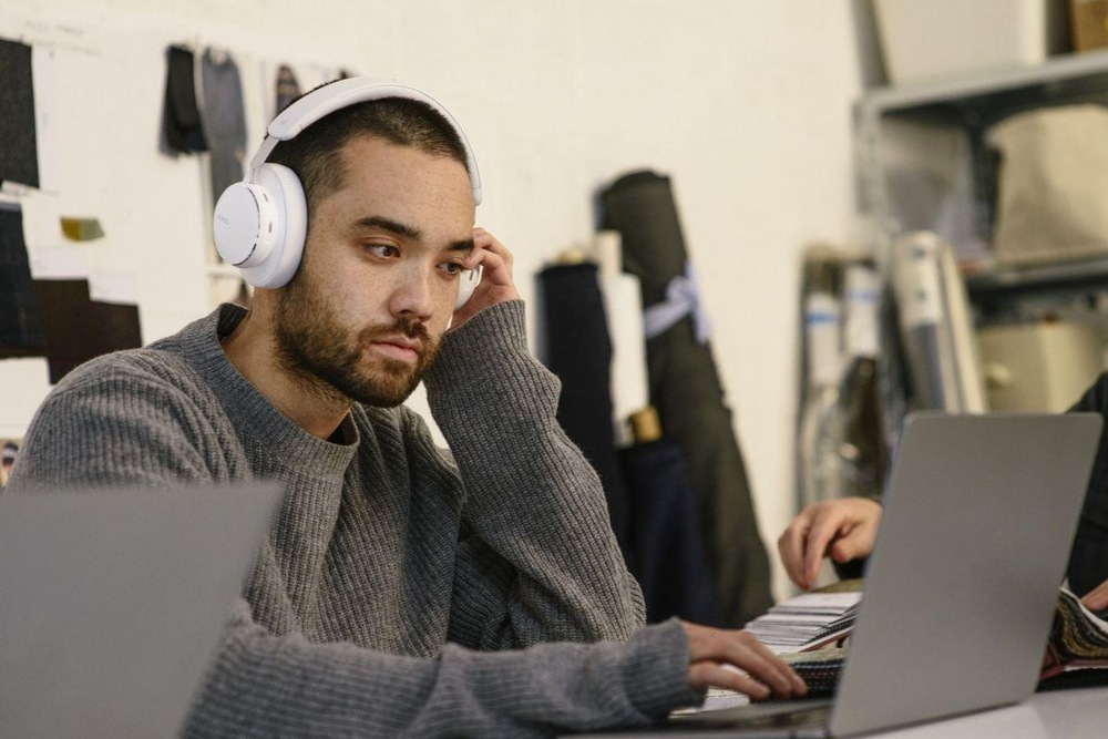 Sluchátka AKG N9 Hybrid bílá Muž pracující v kanceláři telefonuje díky sluchátkům Anker soundcore AKG N9 Hybrid s mikrofony