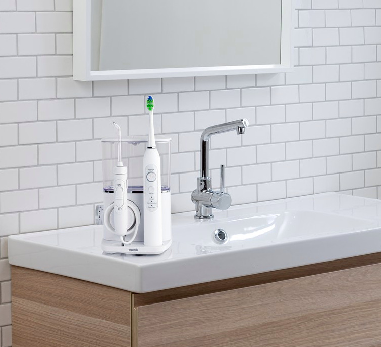 Ústní sprcha se sonickým kartáčkem Waterpik CC04EU umístěná vedle koupelnového umyvadla