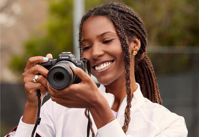Žena fotografující s kompaktní bezzrcadlovkou Canon EOS R50