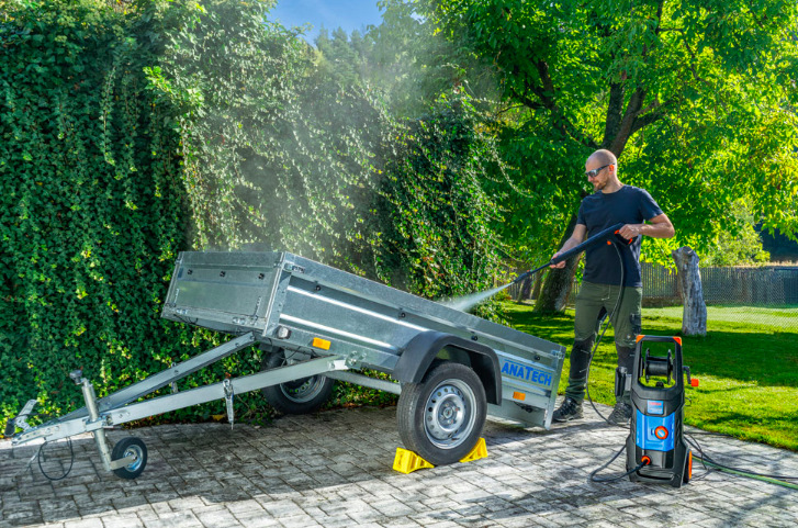 Muž čistí přívěsný vozík vysokotlakým čističem Narex ECT 460 na dvoře