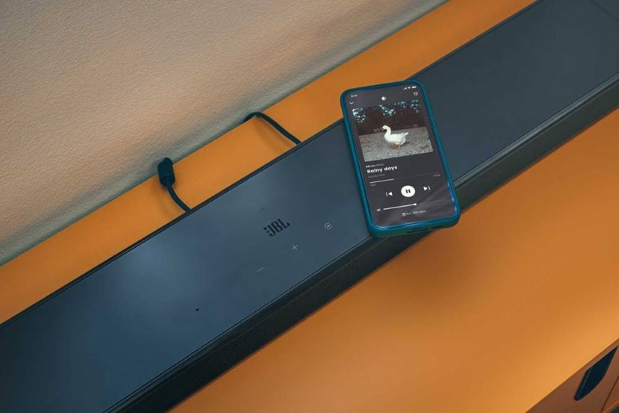 Telefon, který streamuje hudbu, ležící na soundbaru JBL BAR 800 MK2