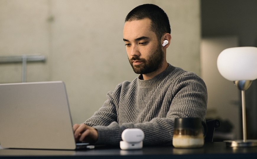 Sluchátka AKG N5 Hybrid bílá Muž pracující na notebooku má v uchu sluchátko AKG N5 Hybrid