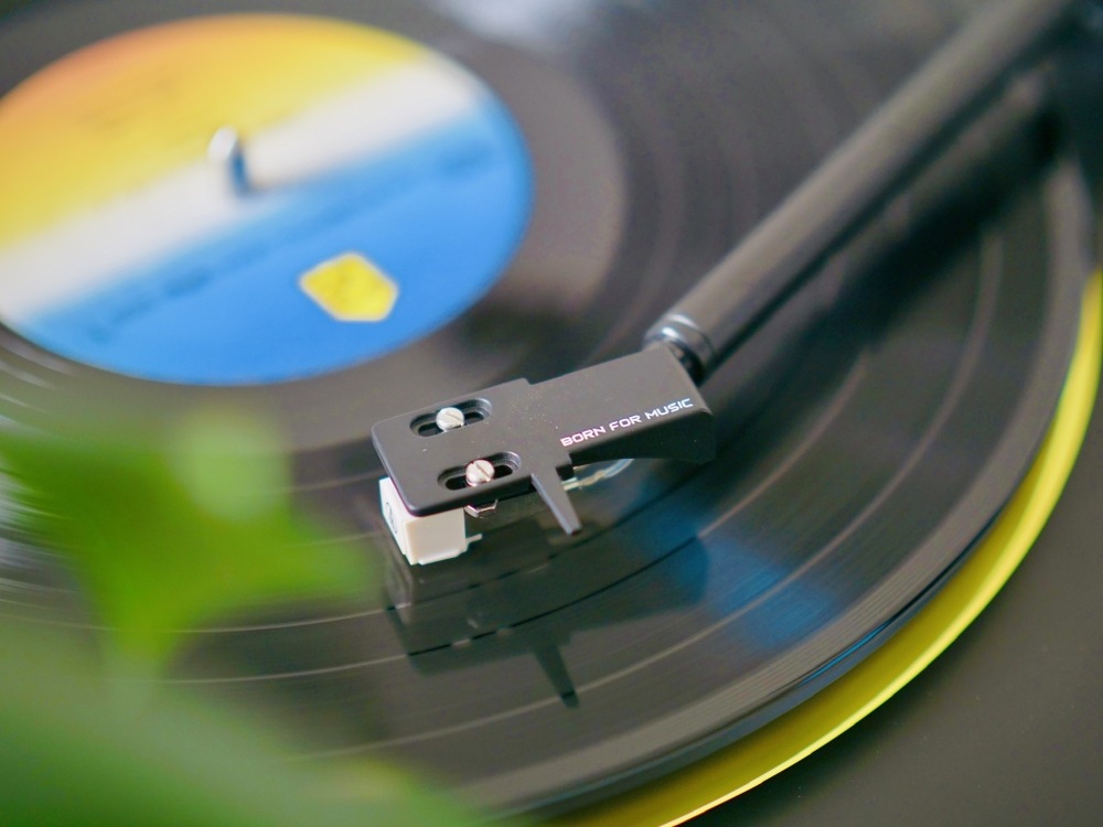 Detailní záběr na jehlu přenosky dosedající na vinylovou desku při přehrávání.