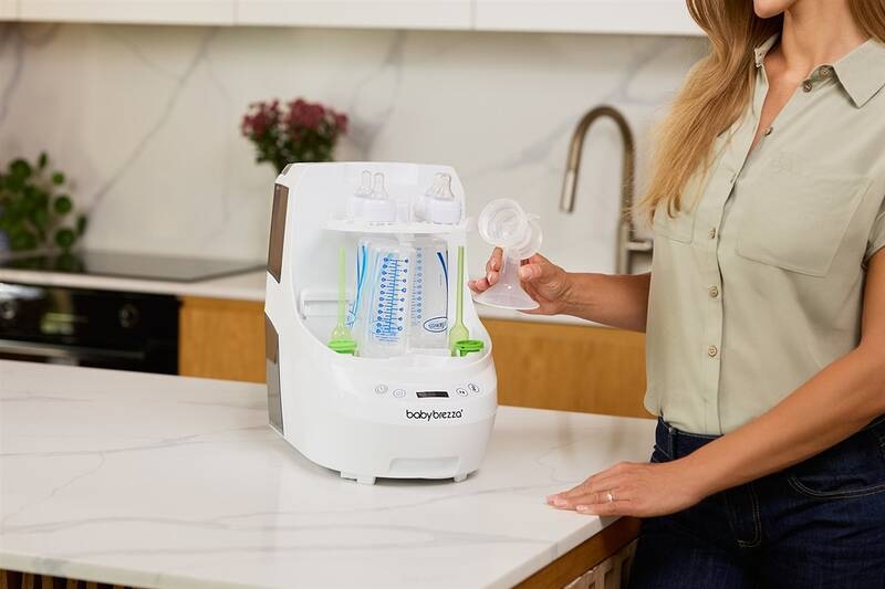 Sterilizátor Baby Brezza Bottle Washer White bílý Sterilizátor Baby Brezza Bottle Washer White je umístěný v kuchyni a žena do něho vkládá dětské příslušenství.