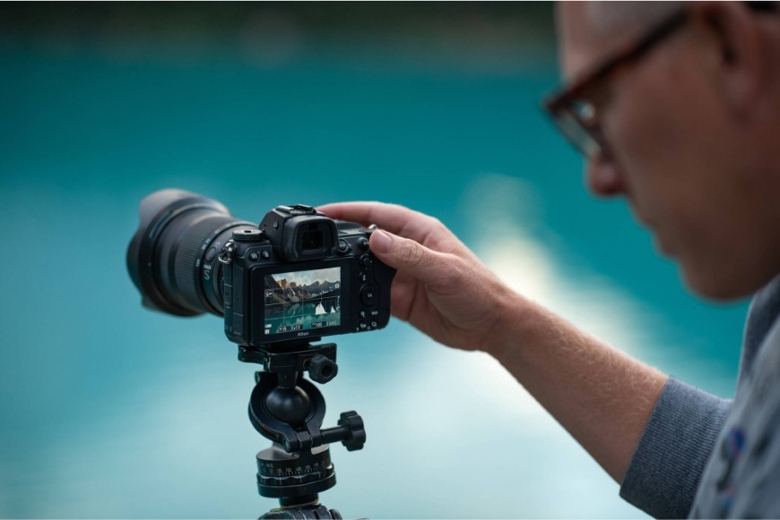 Muž nastavuje fotoaparát na stativu vybavený objektivem NIKKOR Z 24–120 mm f/4 S