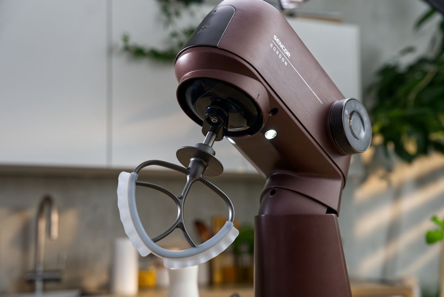 Detailní záběr na celokovový kuchyňský robot značky Sencor ve fialovém provedení. Ve spodní části má zařízení LED osvětlení pro lepší přehled při přípravě.
