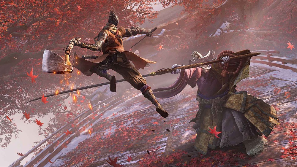 Záběr ze hry Sekiro: Shadows Die Twice. Hlavní hrdina skáče se zakřivenou sekerou směrem k obrněnému protivníkovi na mostě posetém červenými listy, uprostřed vířících podzimních listů.