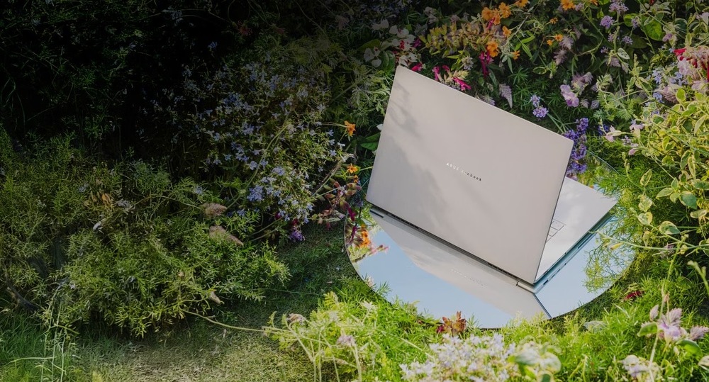 Notebook Asus Zenbook S16 OLED bílý Asus Zenbook S16 položený v zahradě mezi květinami zdůrazňuje spojení designu s přírodou