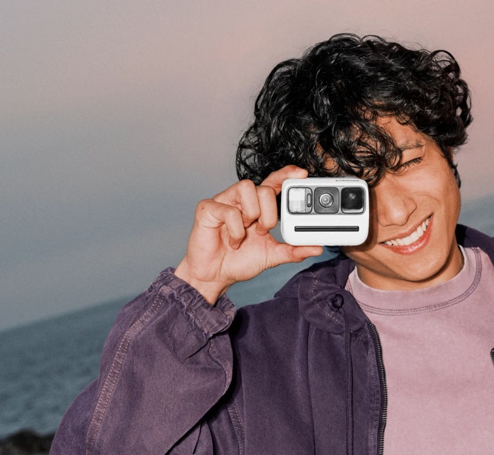 Instantní fotoaparát Polaroid Go Gen 3 fialový Smějící se muž fotografuje pomocí miniaturního fotoaparátu Polaroid Go Gen 3