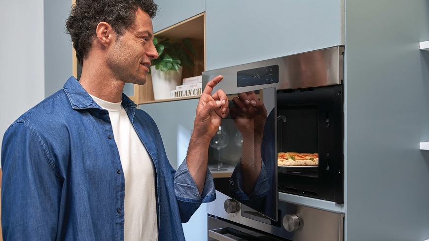 muž si právě ohřál pizzu v mikrovlnné troubě Candy CA38SMXF8XS 
