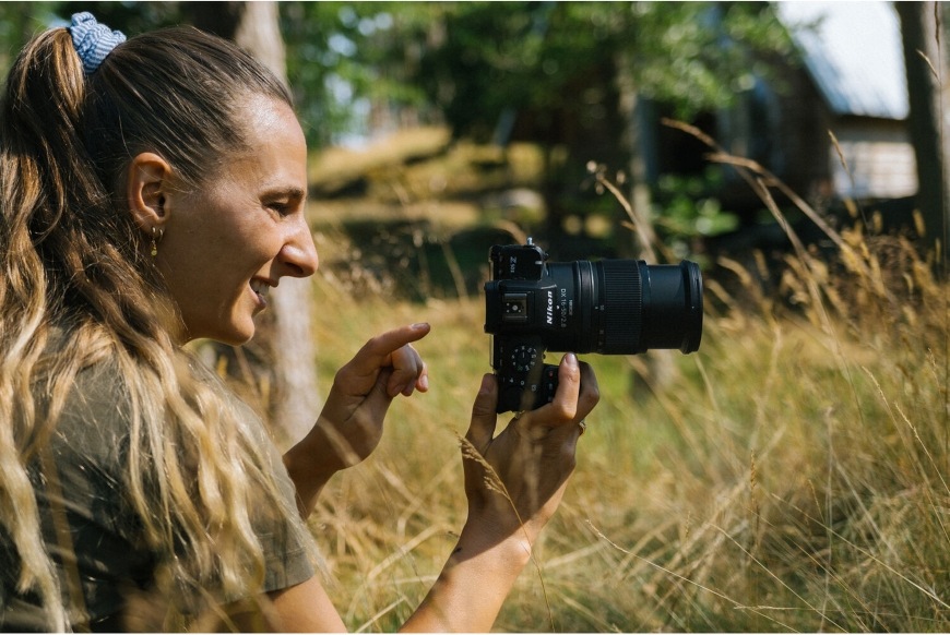 Žena fotografující s objektivem NIKKOR Z DX chlubícím se vysokou světelností