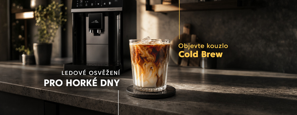Sklenice ledové kávy Cold Brew s mlékem a kostkami ledu na kuchyňské lince, v pozadí automatický kávovar ETA Ristello. Text: Ledové osvěžení pro horké dny – Objevte kouzlo Cold Brew.