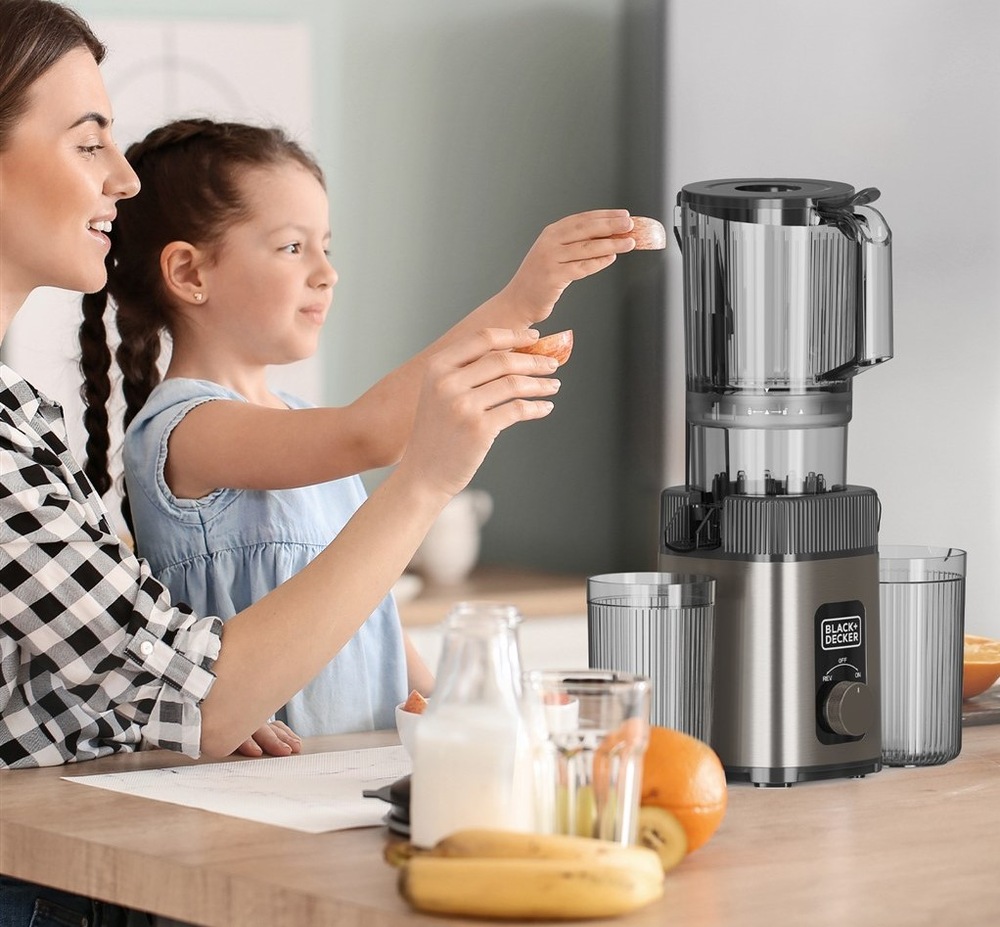 Odšťavňovač Black+Decker BXJE4800E nerez Mamince s přípravou čerstvé šťávy pomáhá také holčička, každá z nich dovnitř vkládá kousek ovoce.
