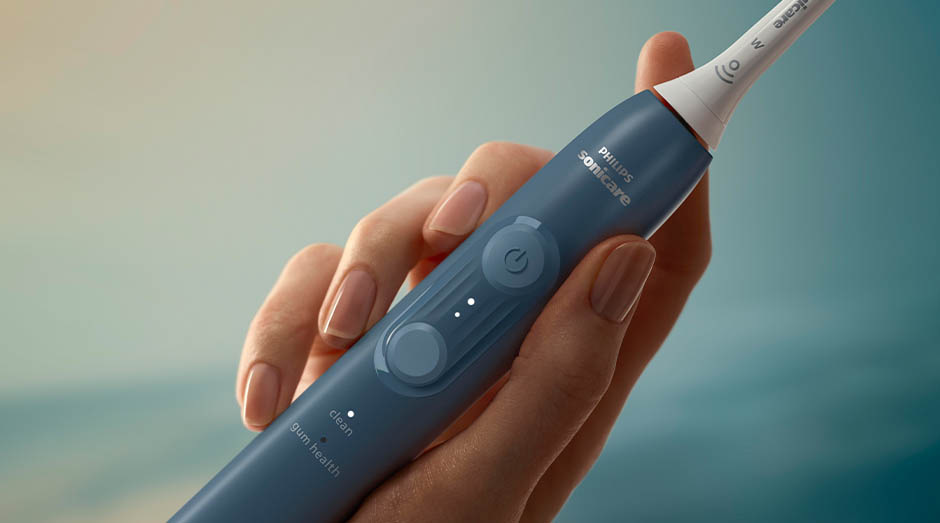 Zubní kartáček Sonicare drží žena v ruce a jdou vidět tlačítka na kartáčku