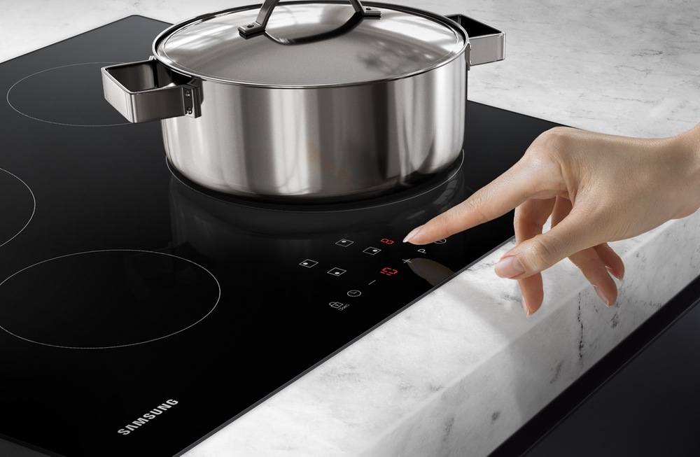 Ruka u ovládacího panelu varné desky indukce Samsung NZ64F3NM1AB/UR