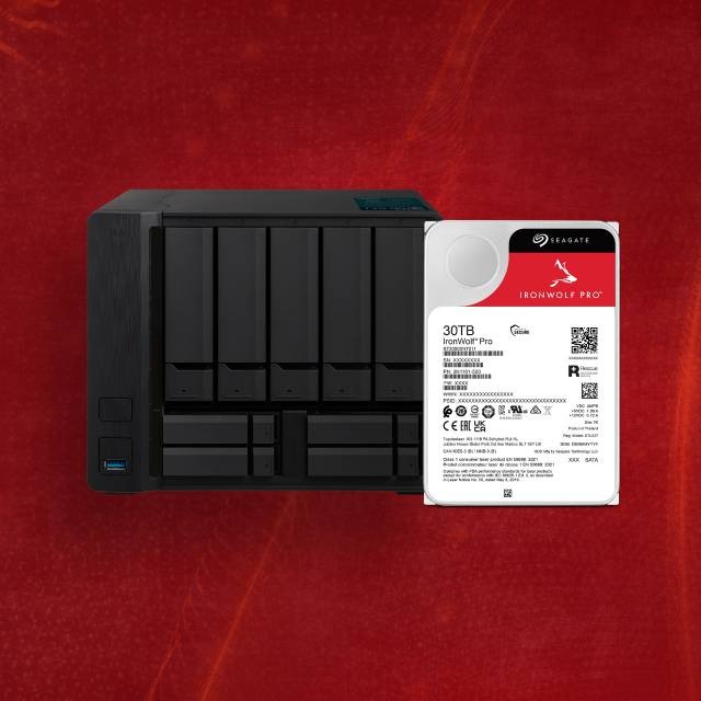 Pevný disk Seagate IronWolf Pro 30 TB je zobrazený vedle černé jednotky NAS s více pozicemi na texturovaném červeném pozadí.
