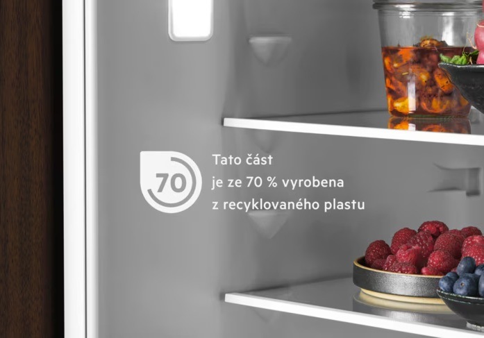 Vnitřek lednice AEG. Na polici dóza s potravinami a miska s malinami a borůvkami. Na stěně nápis – tato část je ze 70 % vyrobena z recyklovaného plastu.