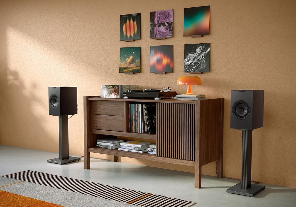 Černé regálové reproduktory KEF Q1 Meta na podlahových stojanech v obývacím pokoji s LP deskami.
