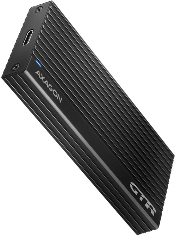 Na obrázku je černý externí box AXAGON THIN RIB pro M.2 SSD zachycený šikmo zepředu. Má velmi úzký, podlouhlý tvar a po celé ploše výrazné podélné žebrování, které mu dává technický a elegantní vzhled. Na čele je USB-C konektor a malá modrá kontrolka, na horní straně nápis AXAGON a označení GTR. Zařízení působí kompaktně, moderně a prémiově.