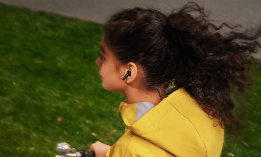 Sluchátka Xiaomi REDMI Buds 8 Active černá Žena jedoucí na kole má v uchu sluchátko Buds 8 Active s potlačením hluku u mikrofonů