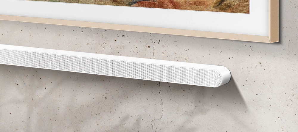 Soundbar Samsung HW-S701D bílý Bílý soundbar Samsung HW-S701D je připevněný na zdi pod televizí Samsung Frame