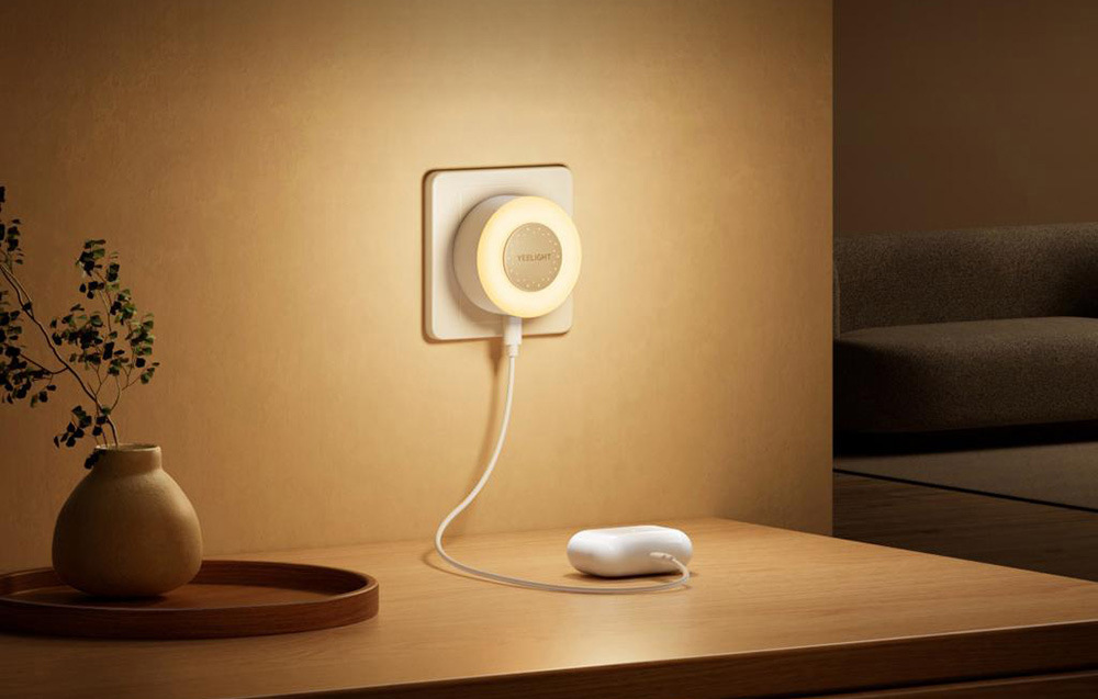 Noční světlo Yeelight Jelly 4 Plus se senzorem soumraku bílé Noční světlo Yeelight Jelly 4 Plus se senzorem soumraku zapnuté v zásuvce a nabíjející sluchátka přes USB