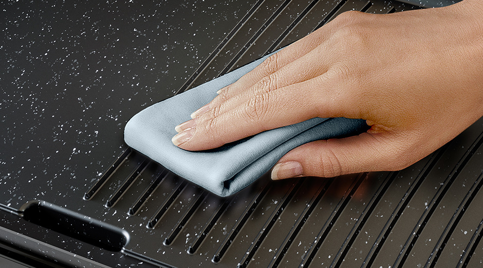 Žena utírá hadříkem nepřilnavou grilovací plochu grilu Philips HD6222/90