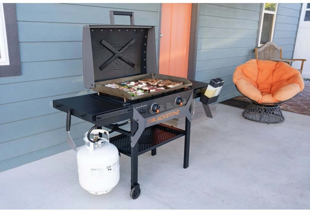 Grilování masa, chřestu a zeleniny na otevřeném grilu Blackstone 28" Omnivore venku.