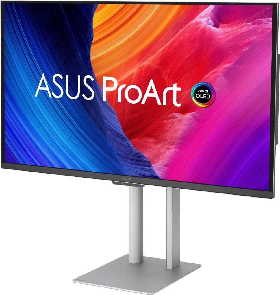Na obrázku je monitor Asus ProArt OLED PA27UCDMR 27" z předního šikmého pohledu. Displej má tenký černý rámeček a stojí na stříbrném výškově nastavitelném stojanu s plochou základnou. Na obrazovce je barevná grafika s nápisem ASUS ProArt a logem OLED, která kombinuje modré, oranžové, červené a fialové odstíny. Monitor působí elegantně a profesionálně, vhodný pro grafiku, úpravu fotografií a práci s obrazem.