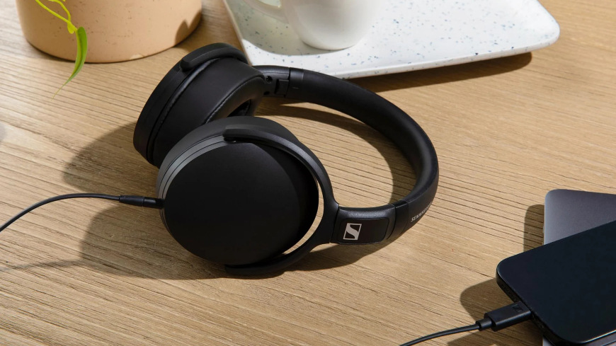 Sluchátka Sennheiser HD400U černá Detail stolu se smartphonem připojeným pomocí kabelu k obloukovým sluchátkům Sennheiser HD400U