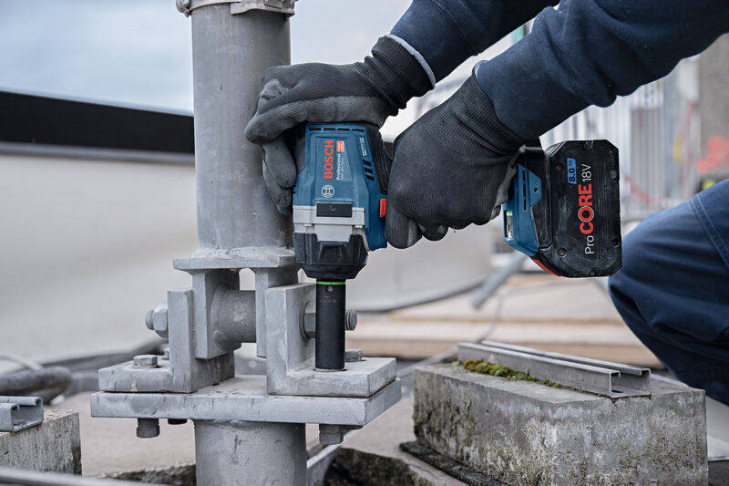 Utahovák rázový Bosch Professional GDS 18V-750 C (s baterií) Pohled zblízka na ruce muže, který drží Rázový utahovák Bosch Professional GDS 18V-750 při práci.