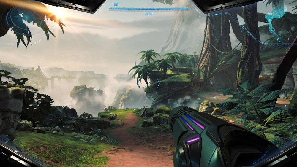 Záběr ze hry Metroid Prime 4: Beyond. Pohled z první osoby s futuristickou zbraní namířenou vpřed v bujné, mimozemské džungli s vysokými stromy, hustým porostem a měkkým slunečním světlem.