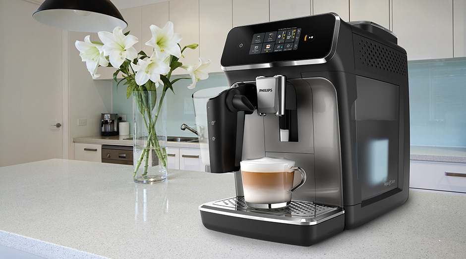 Automatický kávovar Philips EP2339/40 2300 Series stojící na bílé kuchyňské lince vedle vázy s květinami