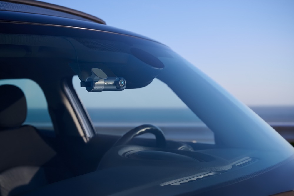 Autokamera 70mai M310 Plus 4K připevněná zevnitř v horní části čelního skla automobilu, kde zabírá jen málo místa ve výhledu řidiče.