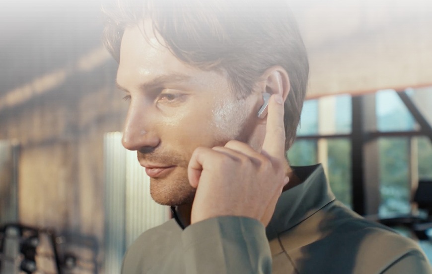 Sluchátka Huawei FreeBuds Pro 5 béžová Muž se dotýká sluchátka Huawei FreeBuds Pro 5 ve svém uchu