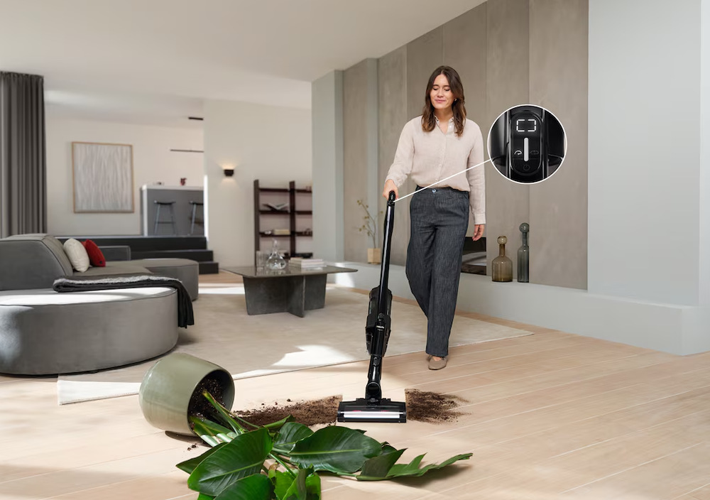Tyčový vysavač Miele Triflex HX3 Hardfloor Casa šedá Žena vysává hlínu od spadnutého květináče s vysavačem Miele Triflex HX3 s režimem Boost