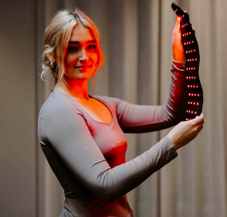 Žena ukazuje vnitřní stranu návleku Swedish Posture InfraEaz s rozsvícenými LED diodami