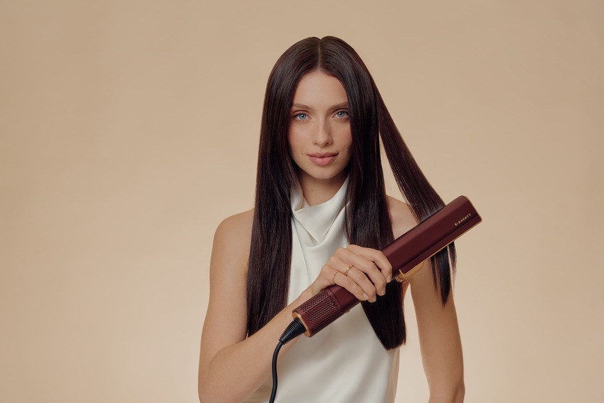 Žehlička na vlasy Garett Beauty AeroGlow hnědá Žena žehlí pramen vlasů.