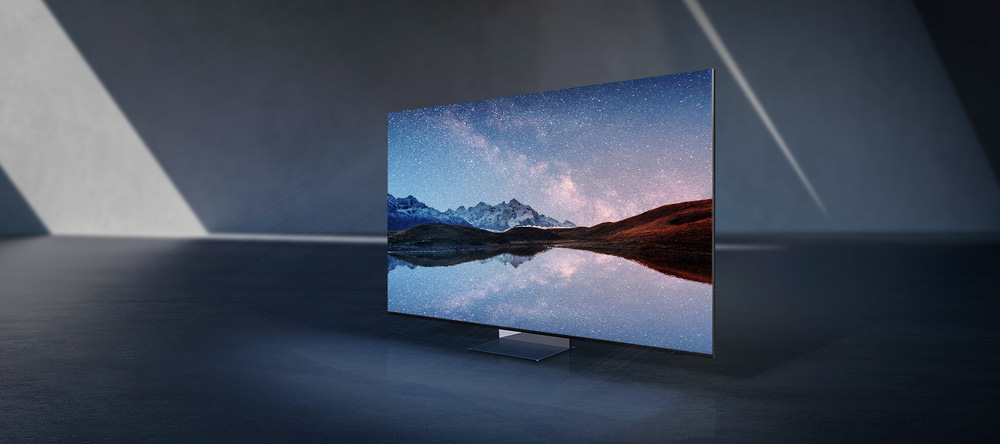 Televize Samsung QE75QN900D postavená v prázdné místnosti, na obrazovce televize je záběr jezera s horami na pozadí