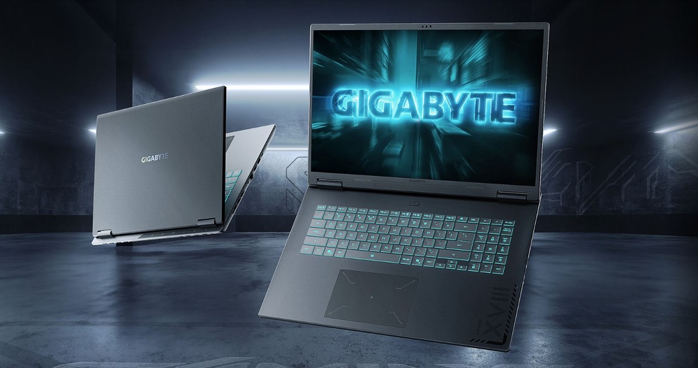 Notebook GIGABYTE GAMING A18 3VHK3CZC94SH černý Elegantní notebook Gigabyte je otevřený a na obrazovce je vidět podsvícená klávesnice a zářící logo „GIGABYTE“. V pozadí je částečně vidět další notebook, který se nachází v moderní, tlumeně osvětlené místnosti.