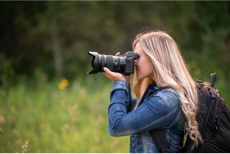 Žena v přírodě fotografuje pomocí všestranného objektivu NIKKOR Z 24–120 mm f/4 S