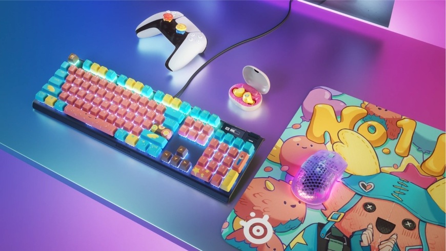 Podložka pod myš SteelSeries QcK Large, Fortnite Guff růžová Myš na podložce QcK Fortnite Guff vedle klávesnice s tematickými krytkami