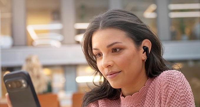 Žena sledující obrazovku telefonu má v uších sluchátka Philips s dotykovým ovládáním, hlasovými asistenty a aplikací pro smartphone