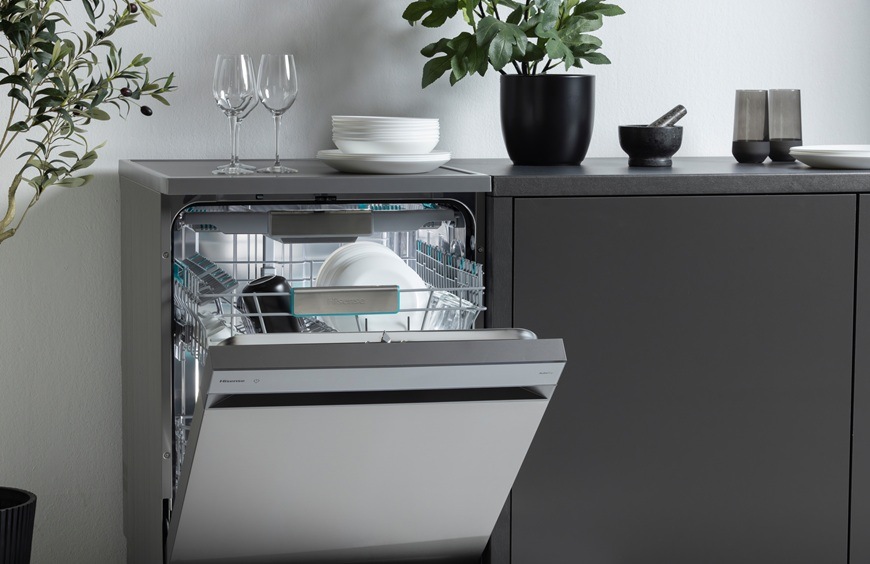 Myčka nádobí Hisense HS673A90BX černá Myčka Hisense má pootevřená dvířka. Na ní je rostlina i nádobí.