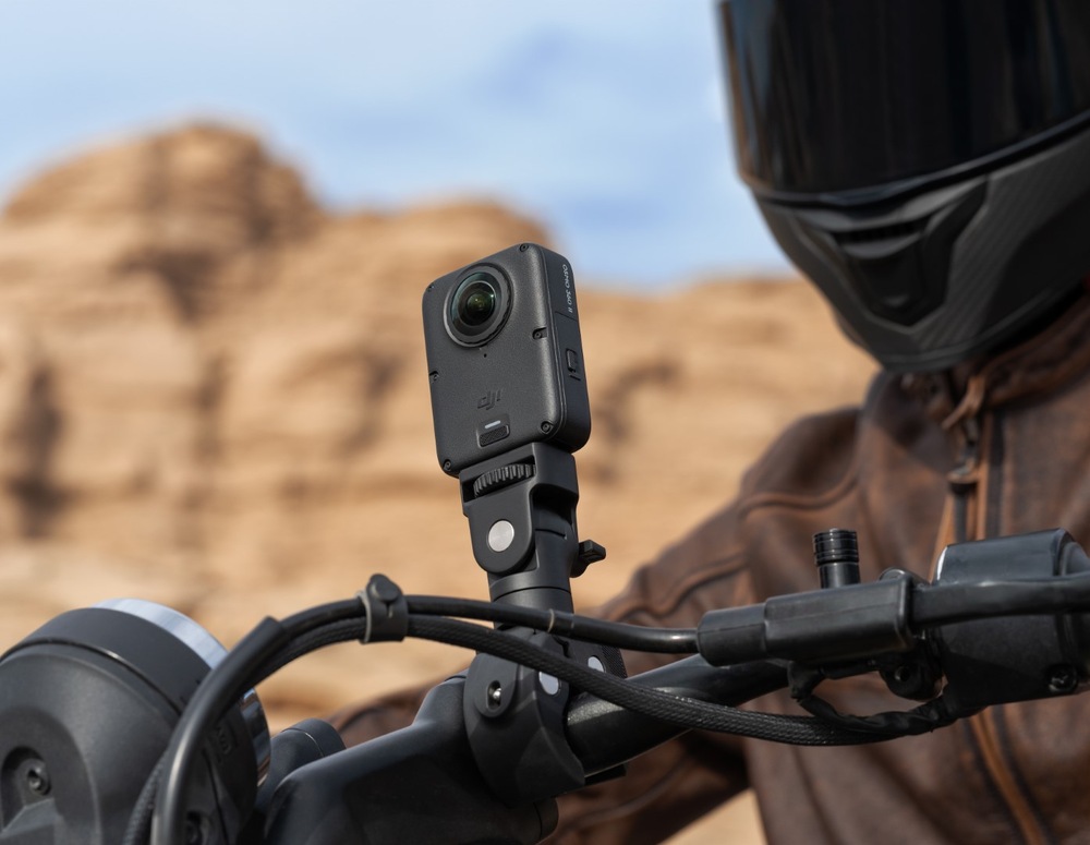 Outdoorová kamera DJI Osmo 360 II Limitless Riding Combo černá Detail kamery DJI Osmo 360 upevněné na řídítkách motocyklu, v pozadí sedí jezdec v helmě